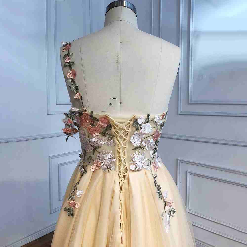 Vestido de fiesta largo color champán con un hombro descubierto y abertura con flores