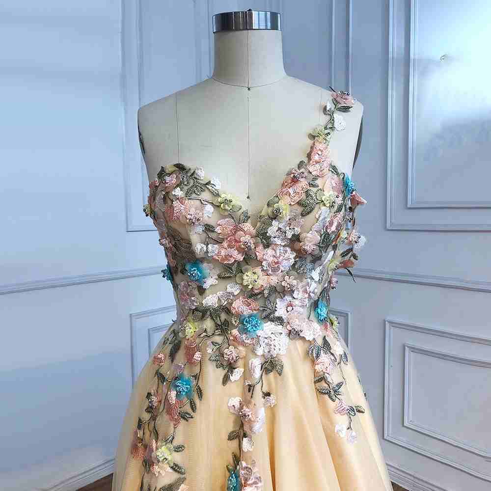 Vestido de fiesta largo color champán con un hombro descubierto y abertura con flores