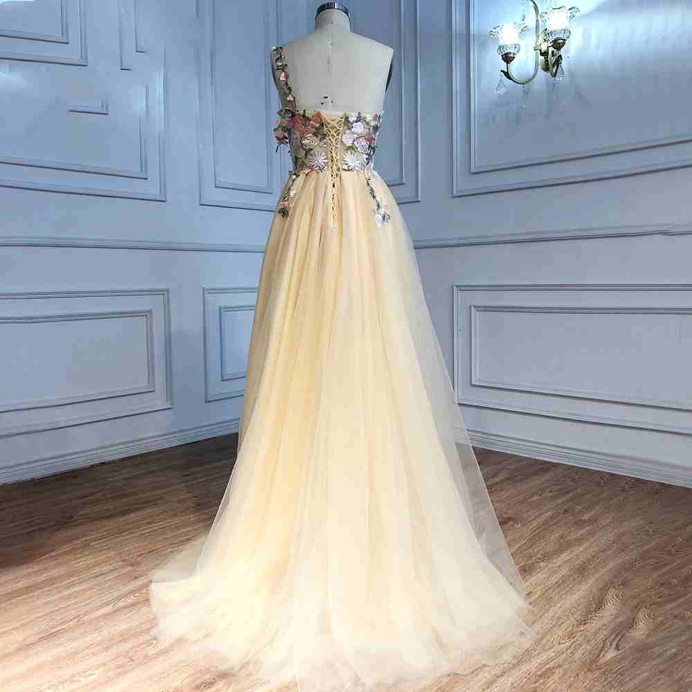 Vestido de fiesta largo color champán con un hombro descubierto y abertura con flores