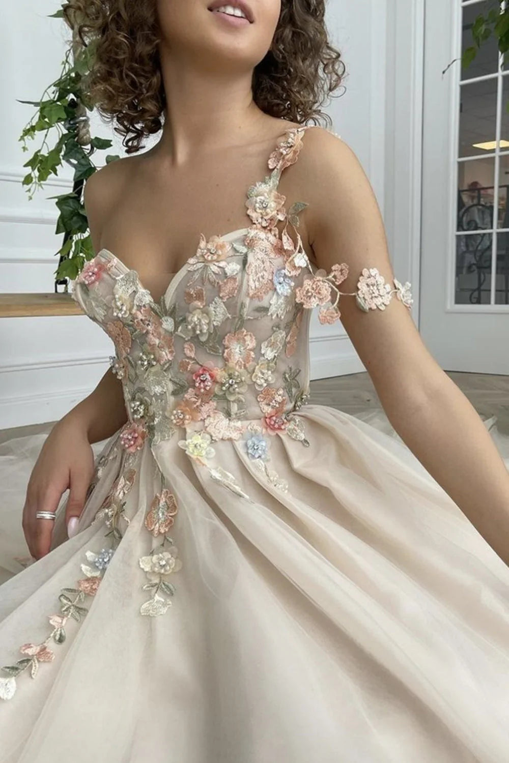 Vestido de fiesta largo color champán con un hombro descubierto y abertura con flores