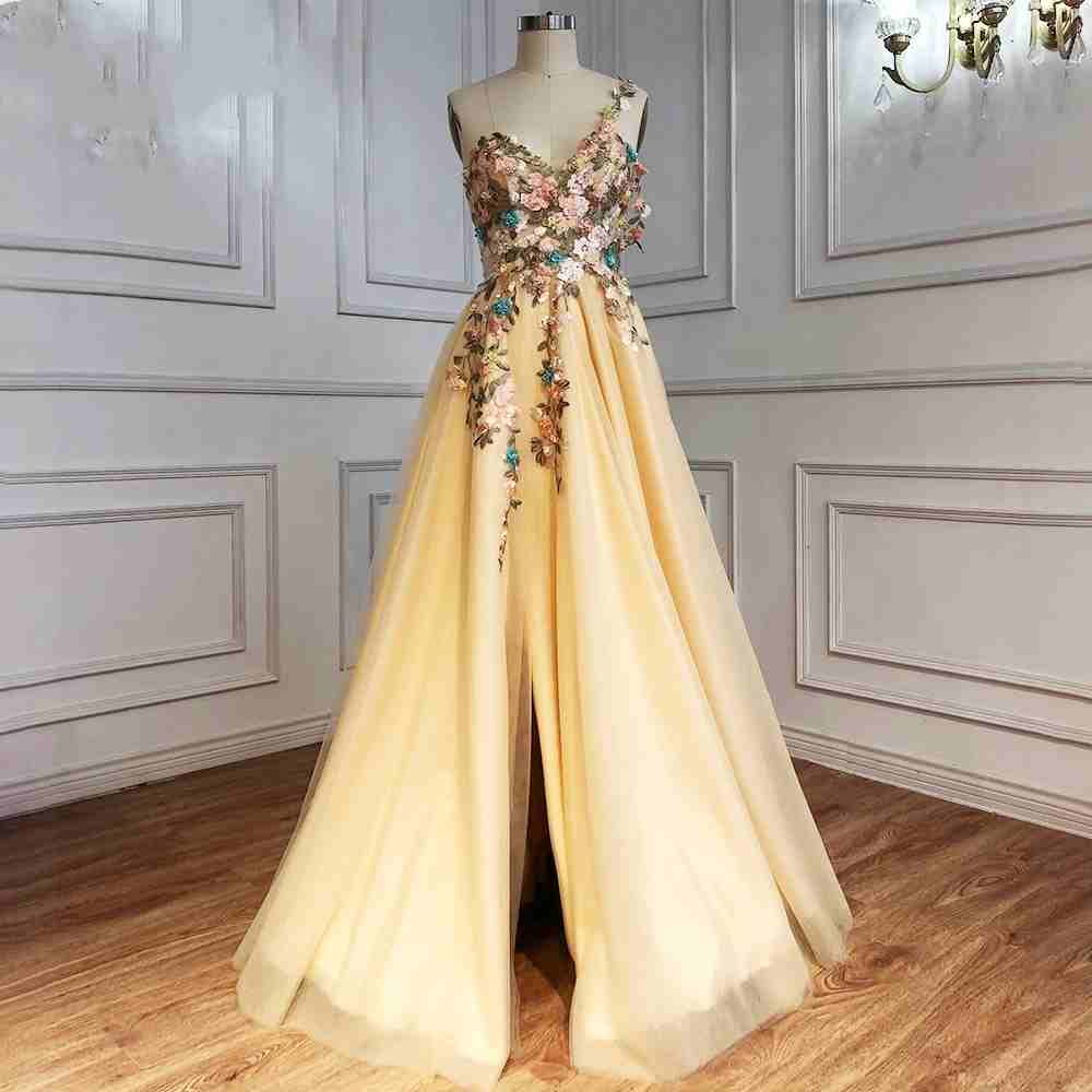 Vestido de fiesta largo color champán con un hombro descubierto y abertura con flores