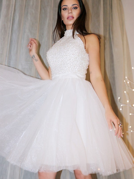 Model showcasing a short A-line halter homecoming dress with intricate beading on the neckline.