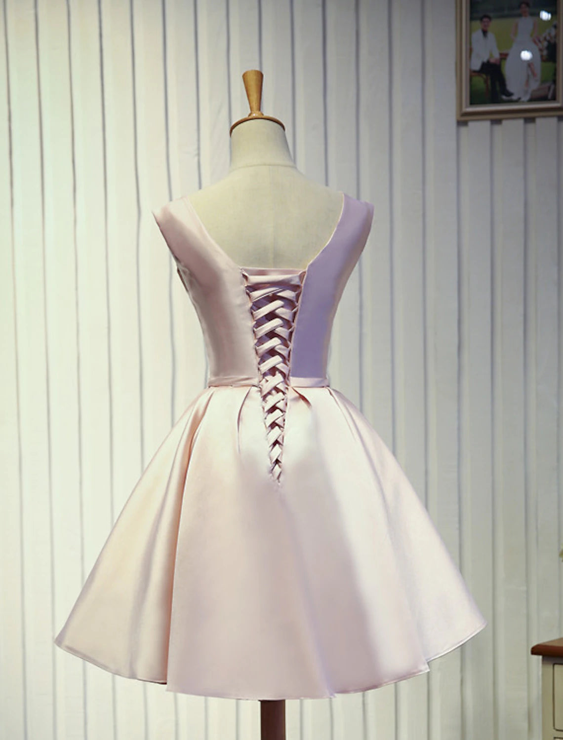 Back view of a sleeveless knee-length prom dress showing backless design.