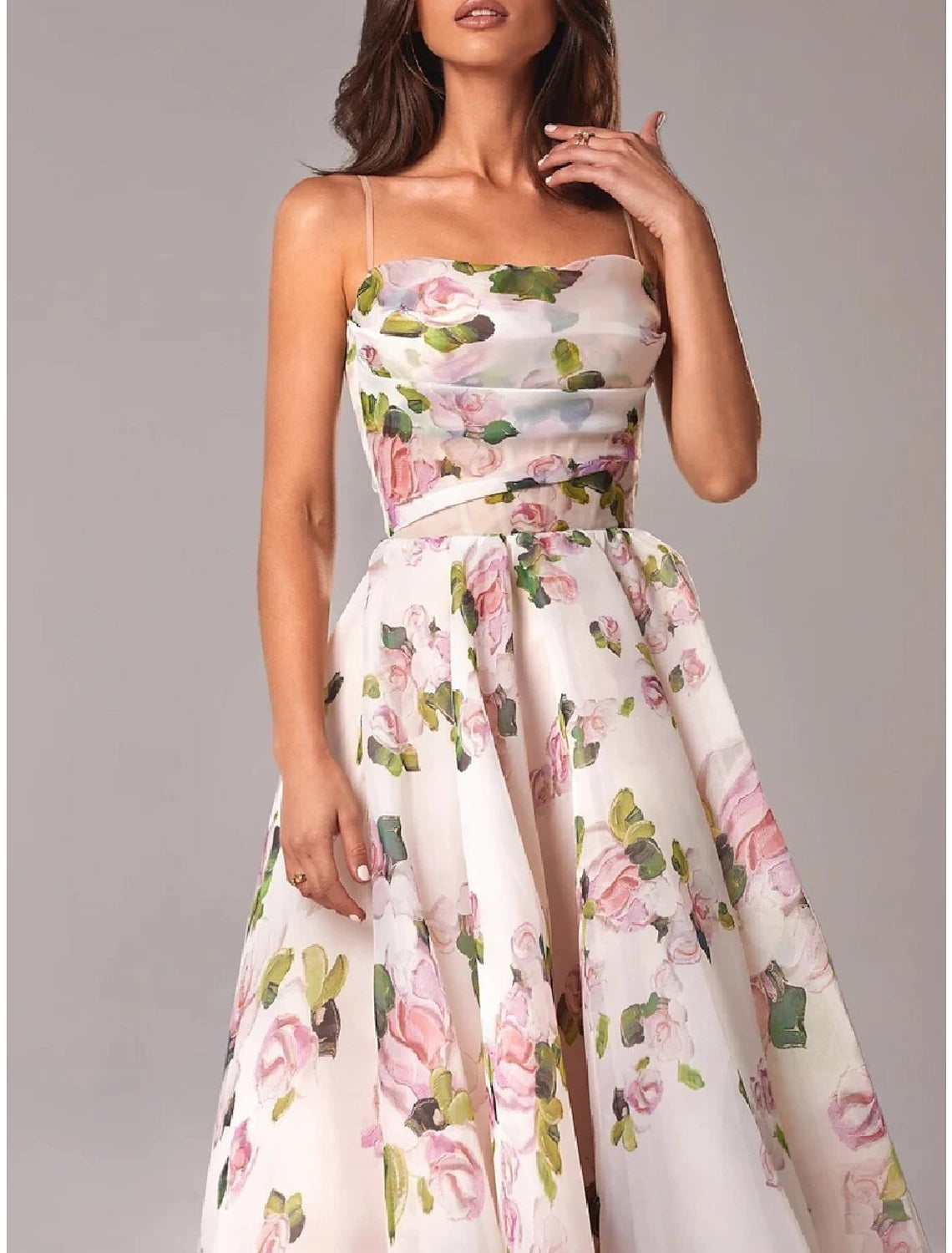 Full view of a model in a sleeveless A-line tea length dress with spaghetti straps.
