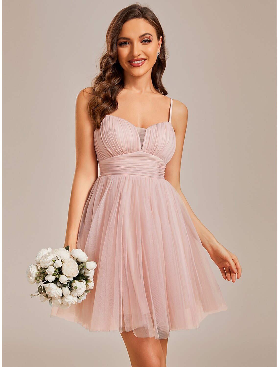 Model wearing a light blue A-line short tulle homecoming dress with spaghetti straps and ruched bodice.