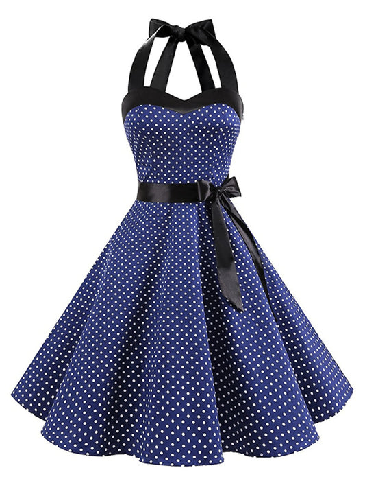 Woman wearing a black polka dot halter neck flare dress, front view.