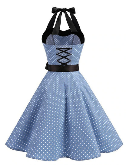 Woman posing in a black polka dot halter neck flare dress.