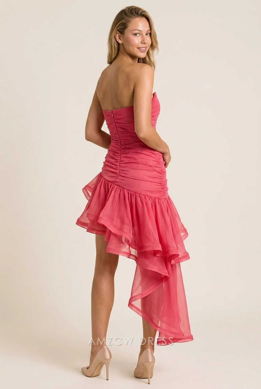 Model posing in a fuchsia high-low dress, highlighting the ruched bodice and asymmetrical hem.