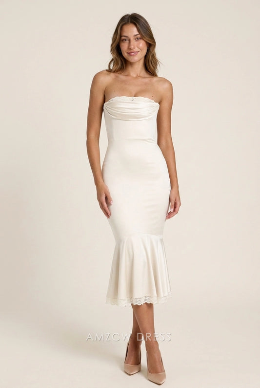 Front view of a woman wearing an elegant ivory strapless mermaid midi prom dress with a draped bodice.