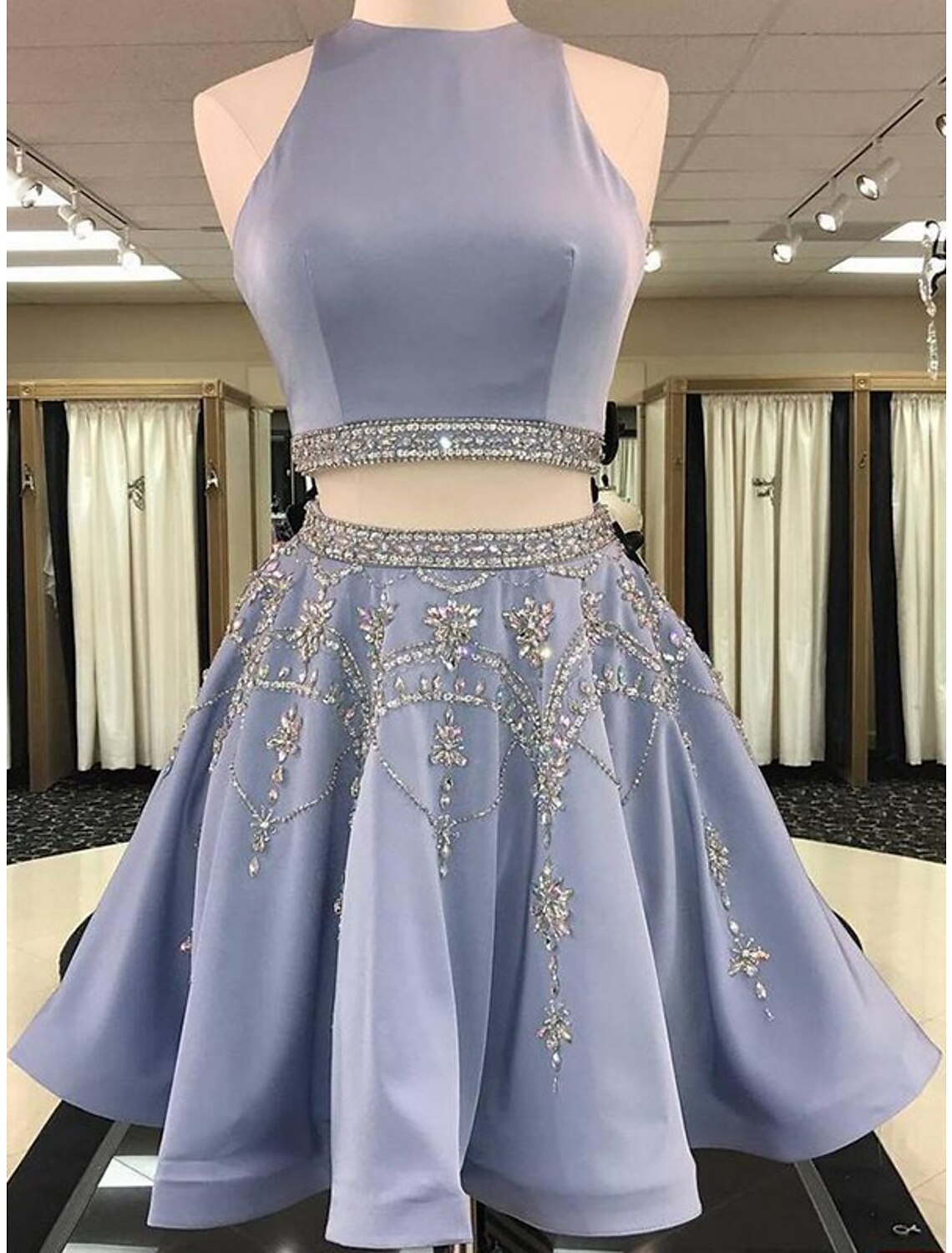 Model wearing a light blue two-piece homecoming dress with a beaded jewel neck top and a satin A-line mini skirt.