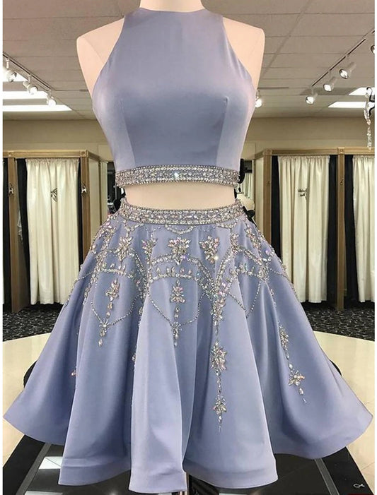 Model wearing an elegant two-piece short homecoming dress in satin with beading, featuring a jewel neck and sleeveless.