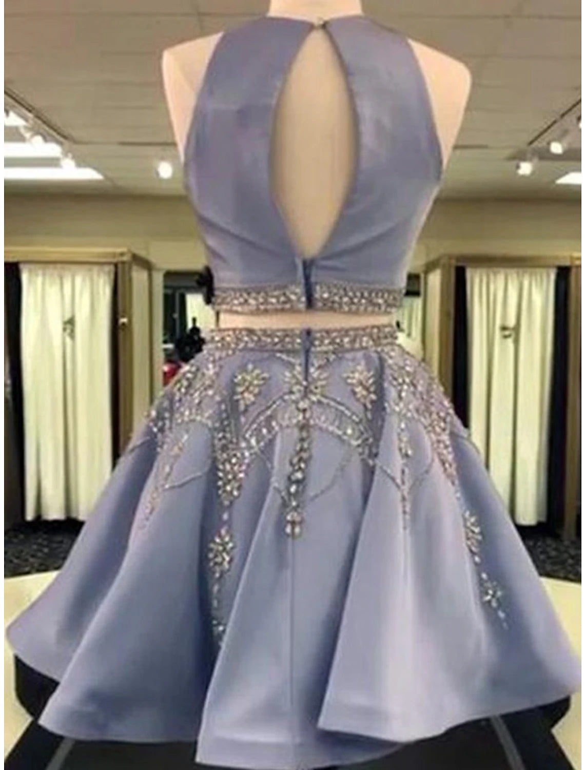 Close-up view of the back of an elegant two-piece short homecoming dress, showcasing the satin fabric and intricate beading.