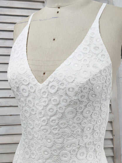 Vestido de fiesta de encaje blanco con escote en V profundo, tirantes cruzados, abertura y cola larga.