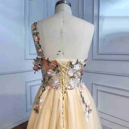 Vestido de fiesta largo color champán con un hombro descubierto y abertura con flores 