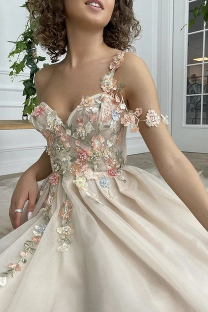 Vestido de fiesta largo color champán con un hombro descubierto y abertura con flores 
