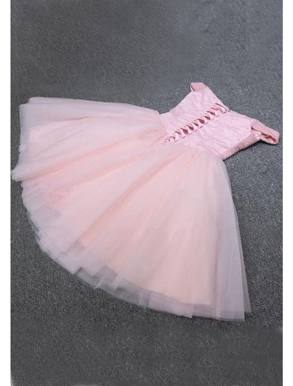 Back view of a pink sequin A-line dress, featuring an off-shoulder neckline and knee-length tulle skirt.