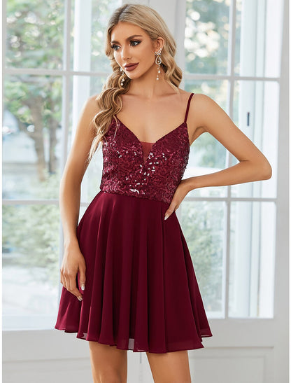 Model wearing a sparkling A-line mini homecoming dress with spaghetti straps.