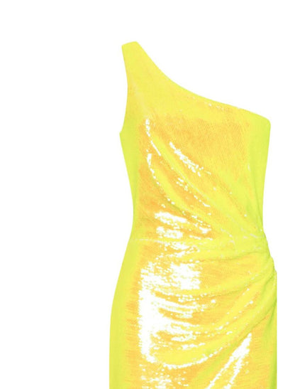 Side view of a woman in a shimmering one-shoulder tea-length sequined dress, showcasing the slit and feather embellishment.