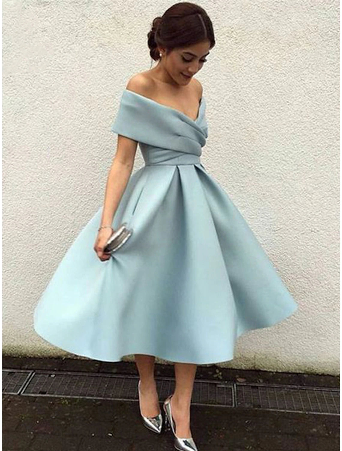 Woman wearing a vintage 1950s A-line tea length cocktail dress with a V-neck and short sleeves.