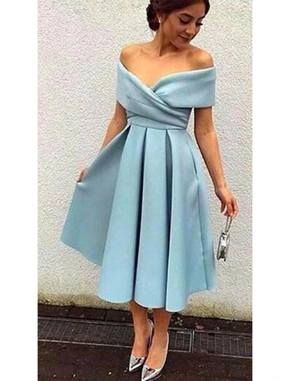 Side view of a woman in a 1950s A-line tea length cocktail dress, showing the pleated skirt.