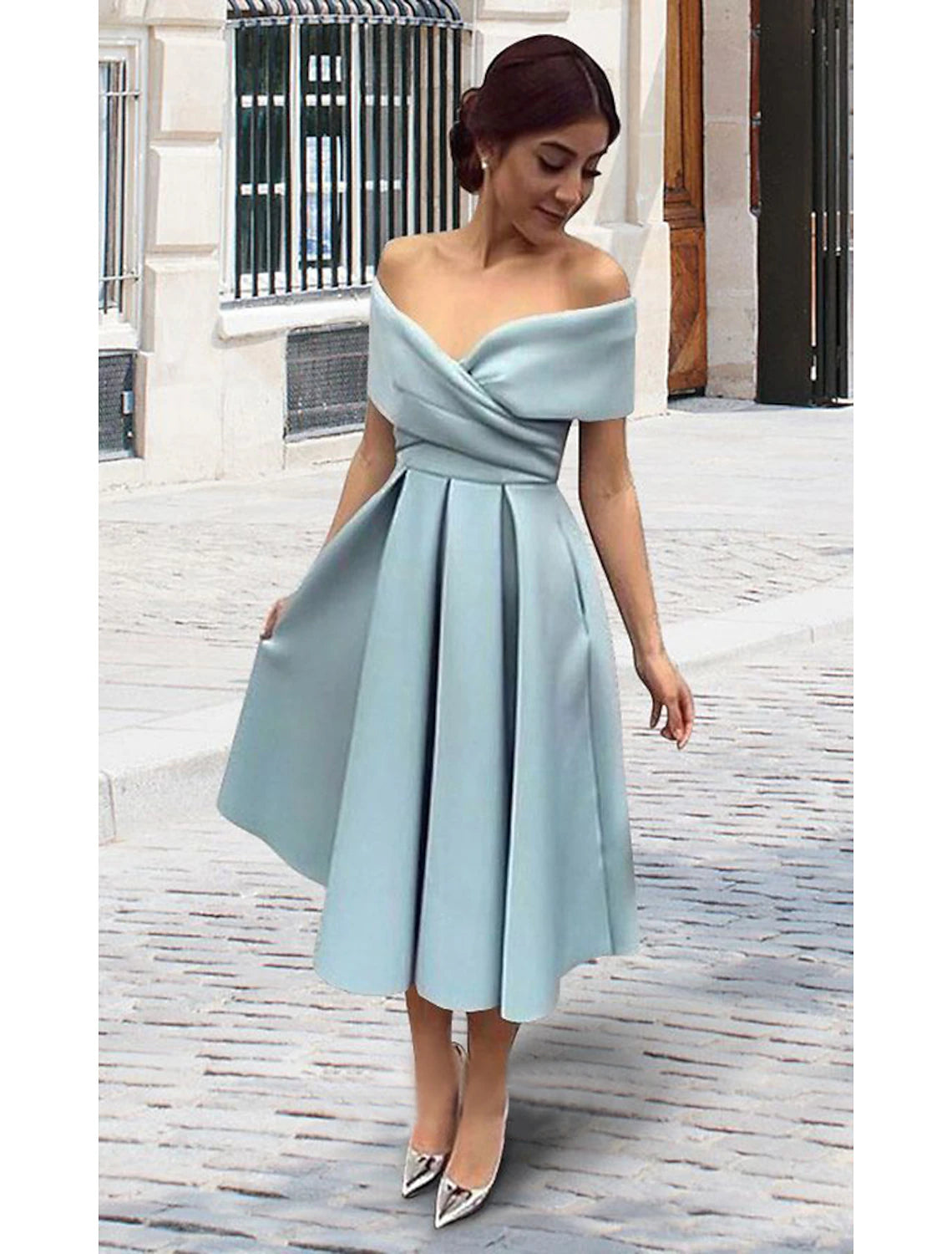 Back view of a woman in a 1950s A-line tea length cocktail dress, highlighting the V-back.