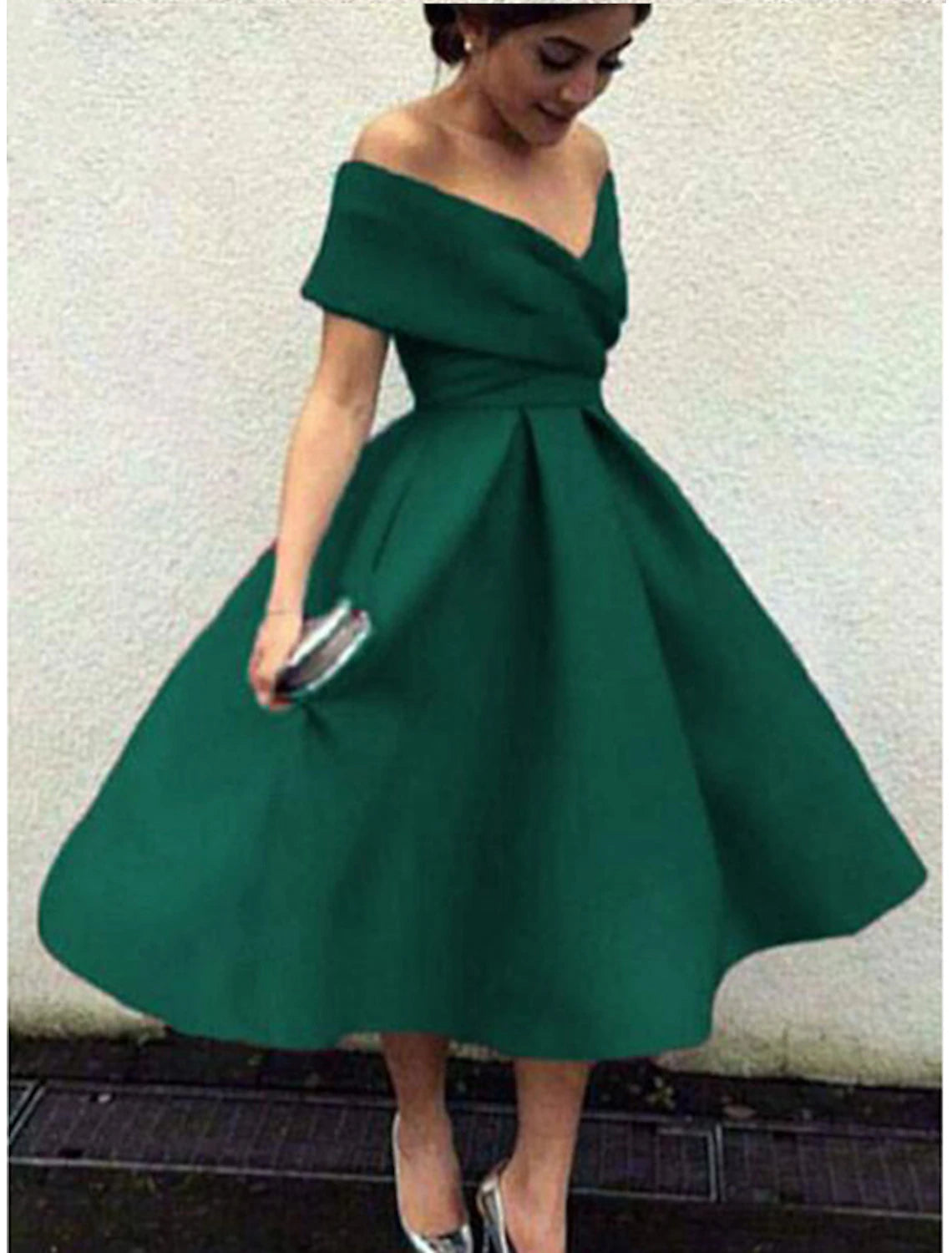 Woman standing gracefully in a 1950s A-line tea length cocktail dress.