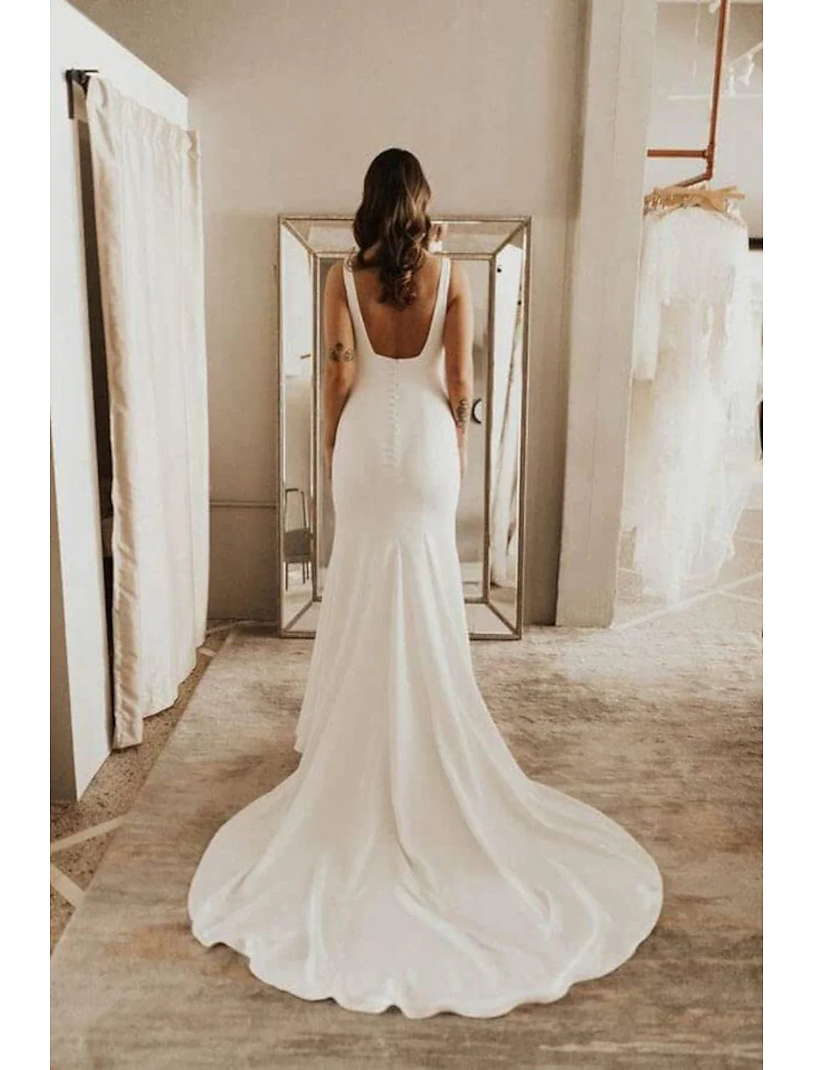 Back view of the white bridal gown, showcasing the elegant court train and camisole straps.