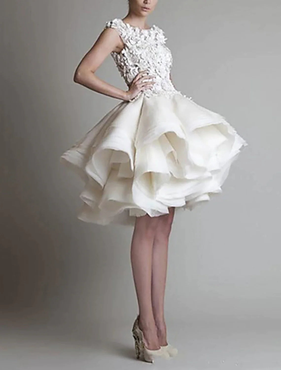 Side view of a model in a puffy tiered white organza dress with floral appliques.