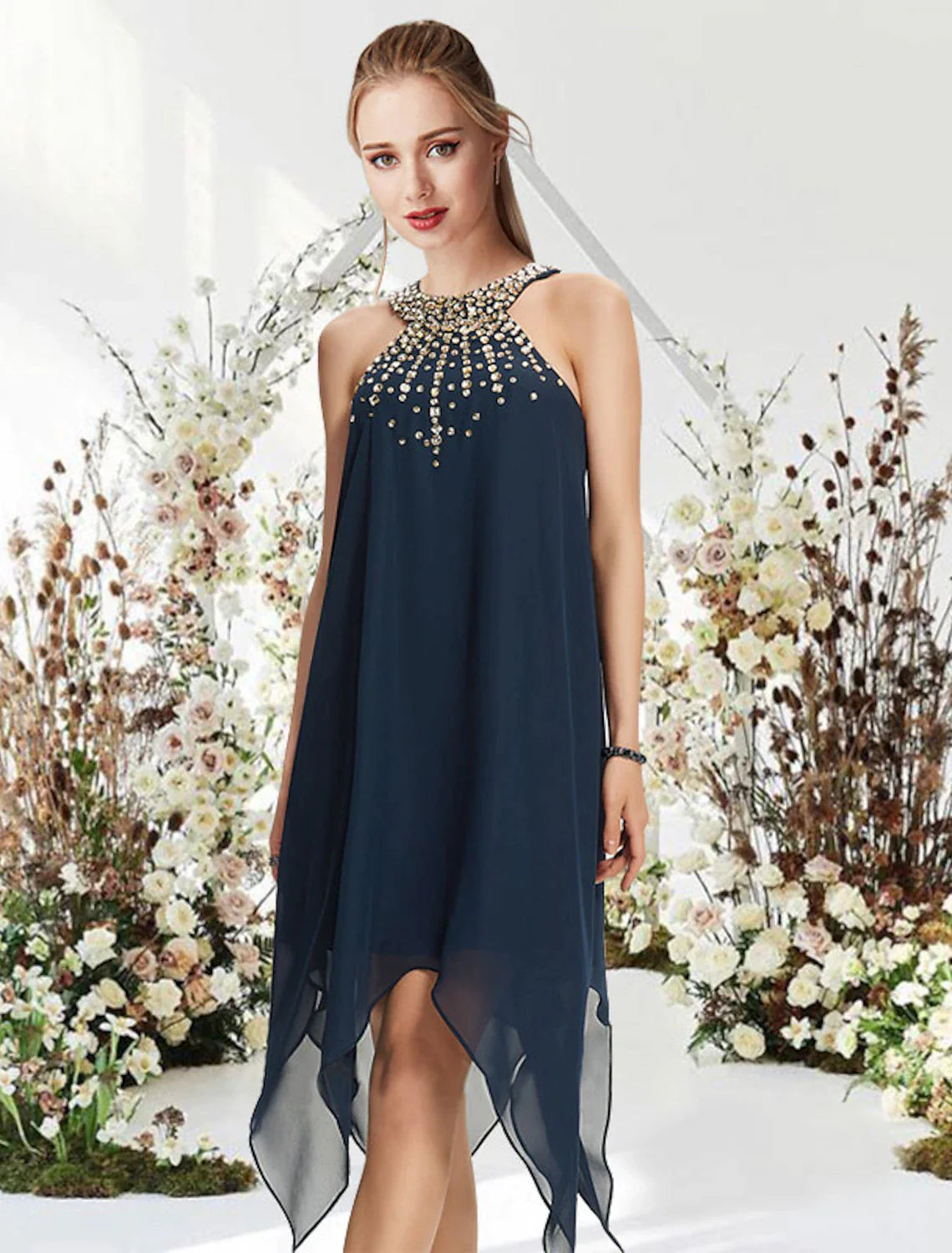 Woman wearing an elegant A-line halter cocktail dress with asymmetrical hem, crystals, and beading, front view.
