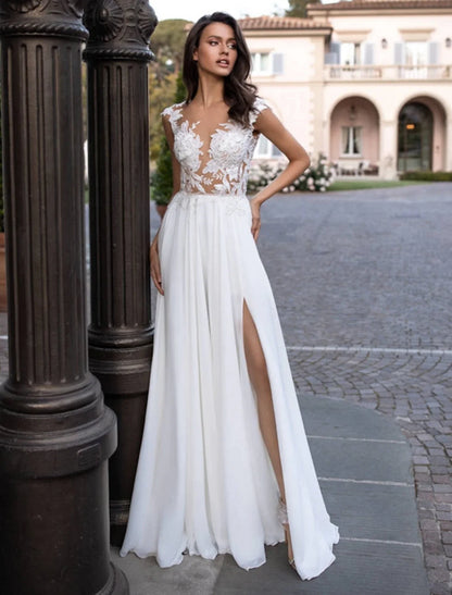 Front view of A-Line chiffon wedding dress with illusion neck, cap sleeves, appliques, and split front.