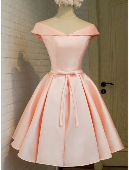 Model wearing an elegant A-line short satin homecoming dress with off-shoulder and strappy details.