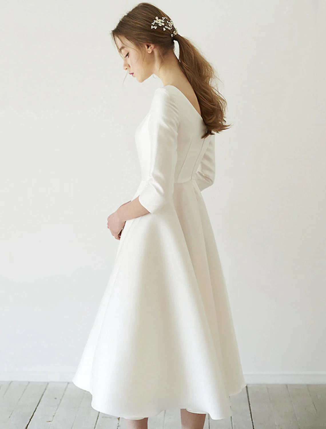 Back view of the satin tea length bridal gown with pleats.