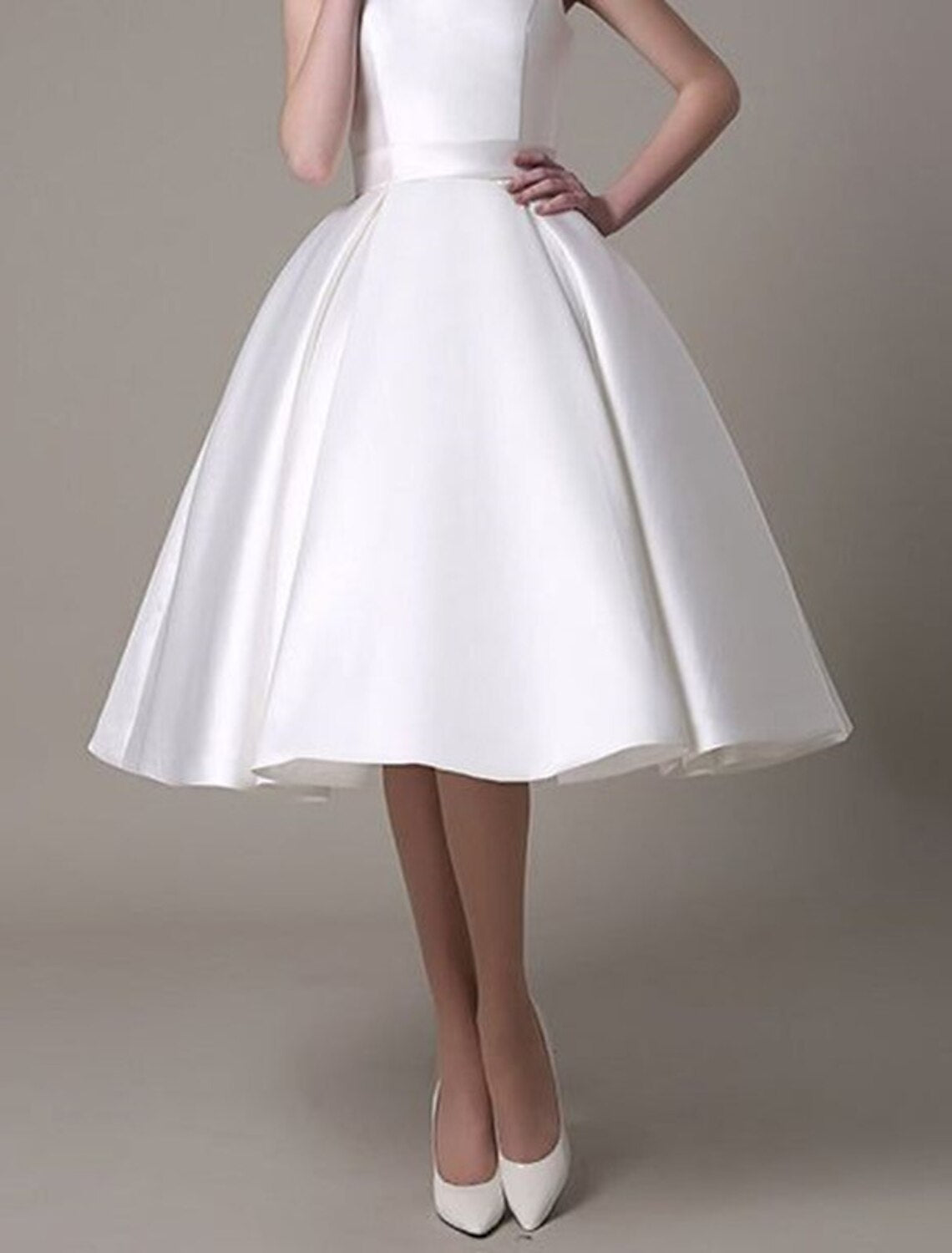 Back view of a model wearing a sleeveless A-line satin cocktail dress, highlighting the square neckline.