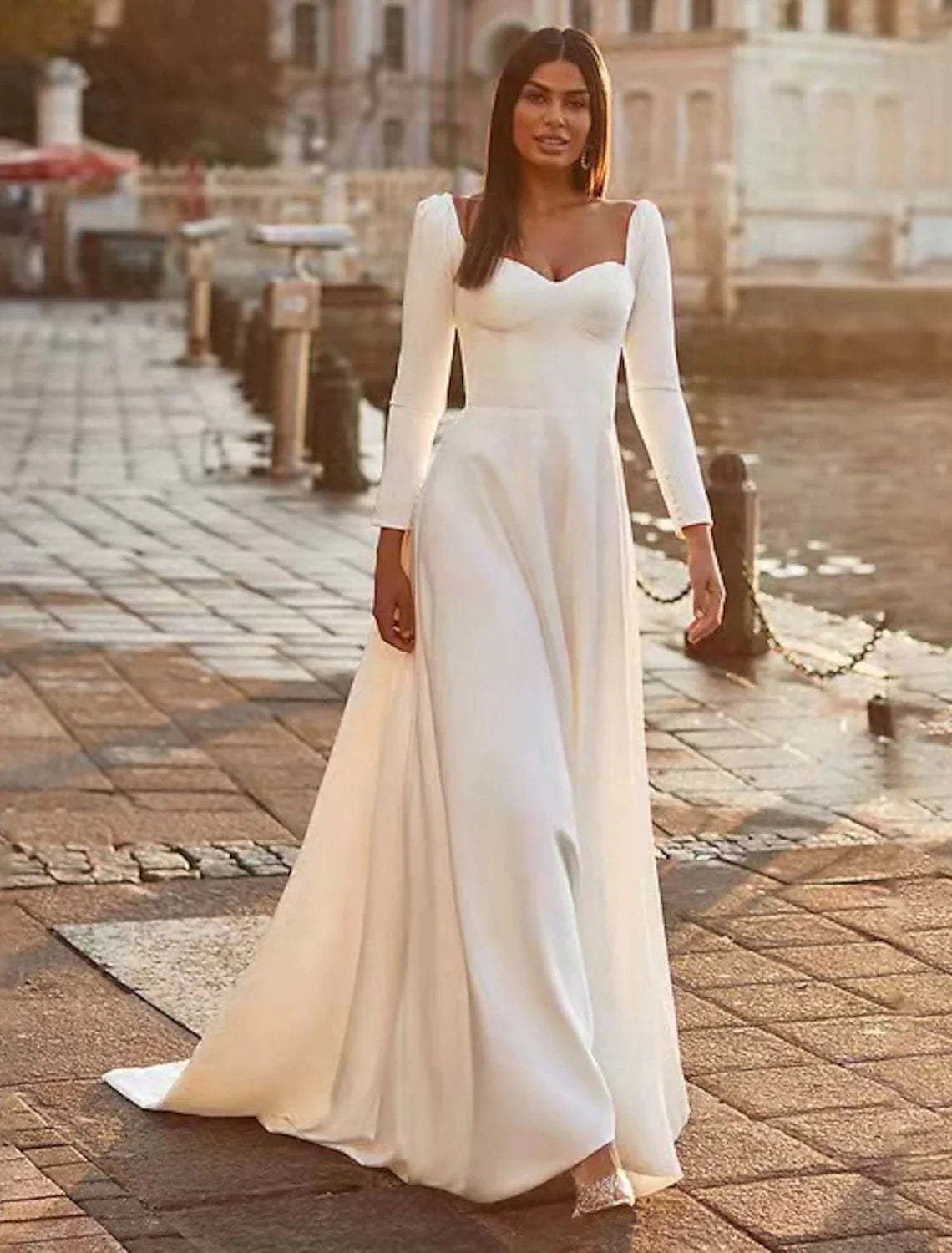 Full view of an elegant A-line sweetheart long sleeve satin wedding dress with a sweep train.