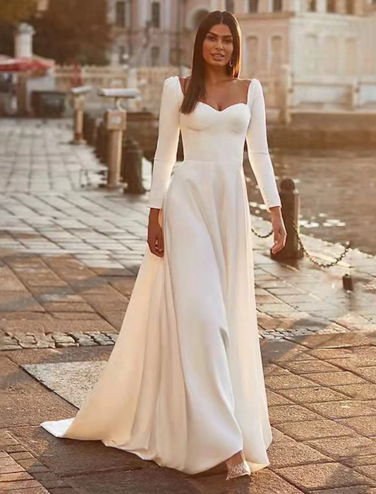 Full view of an elegant A-line sweetheart long sleeve satin wedding dress with a sweep train.