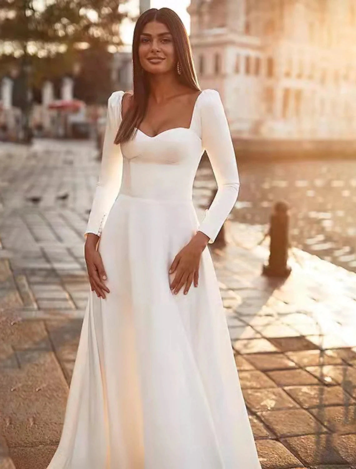Close-up of the sweetheart neckline and long sleeves on the satin wedding dress.