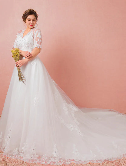 Close-up of the V-neckline and half sleeves of the wedding dress, adorned with lace and crystals.