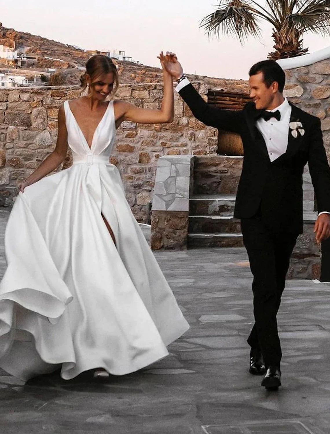 Bride posing in sleeveless satin wedding dress with sashes.