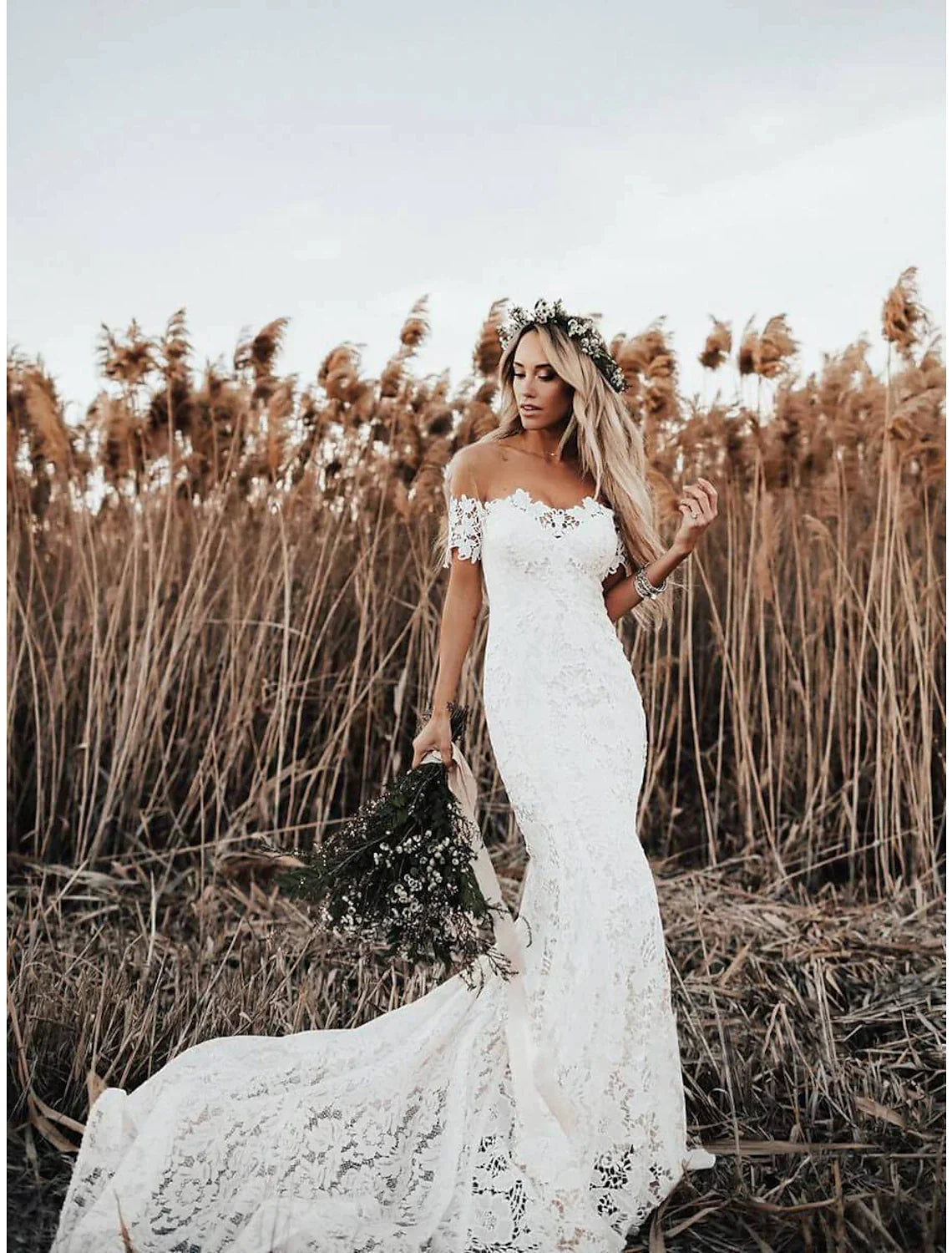 Side view of the bride in the boho mermaid wedding dress with appliques.