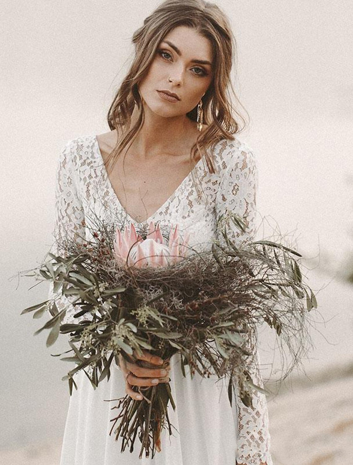 Model wearing an elegant A-line V-neck long-sleeve chiffon wedding dress with a sweep train outdoors.