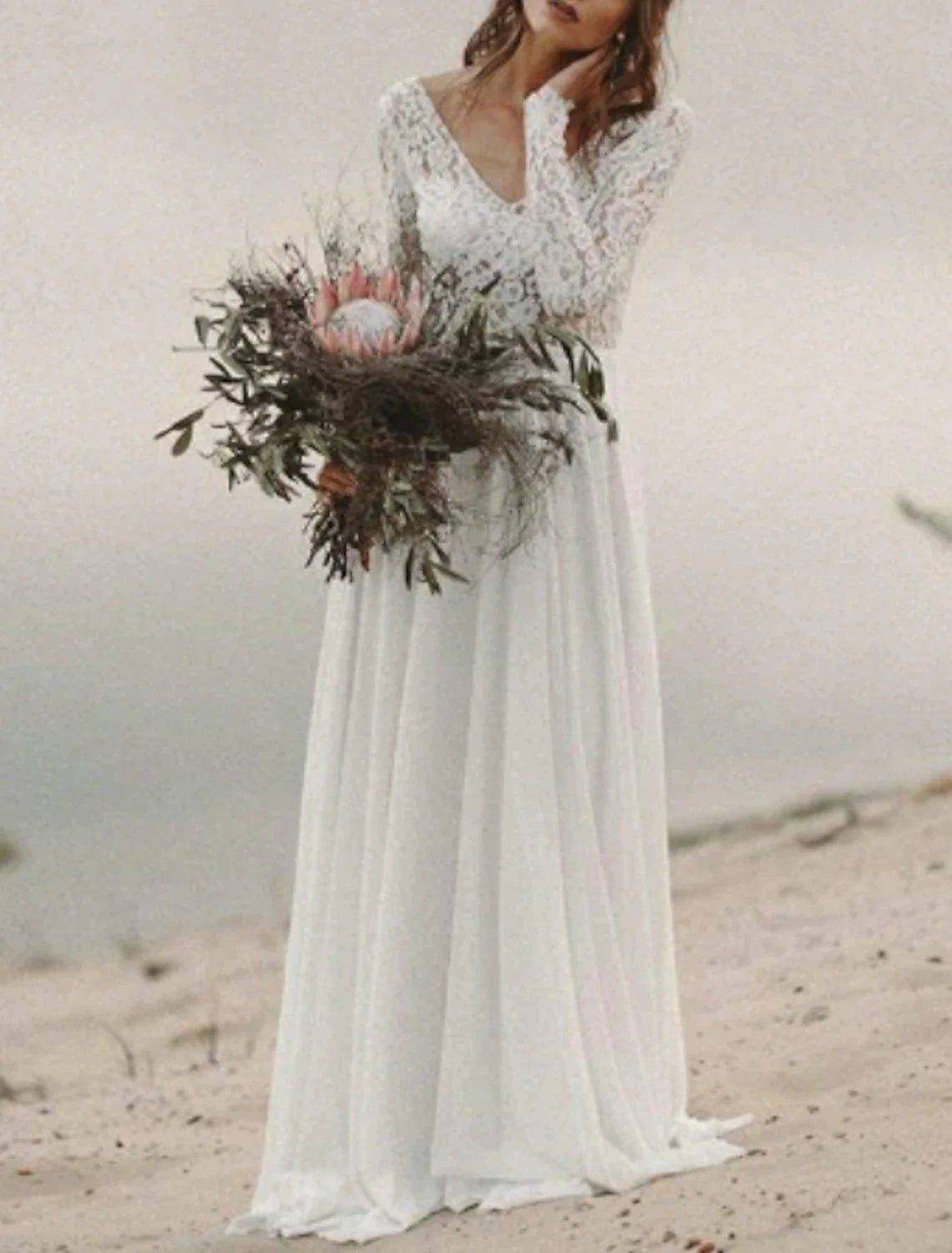 Close-up of the V-neckline and long sleeves of the chiffon wedding dress.