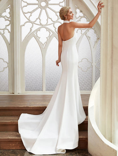 Full length view of a woman posing in a white sheath wedding dress.