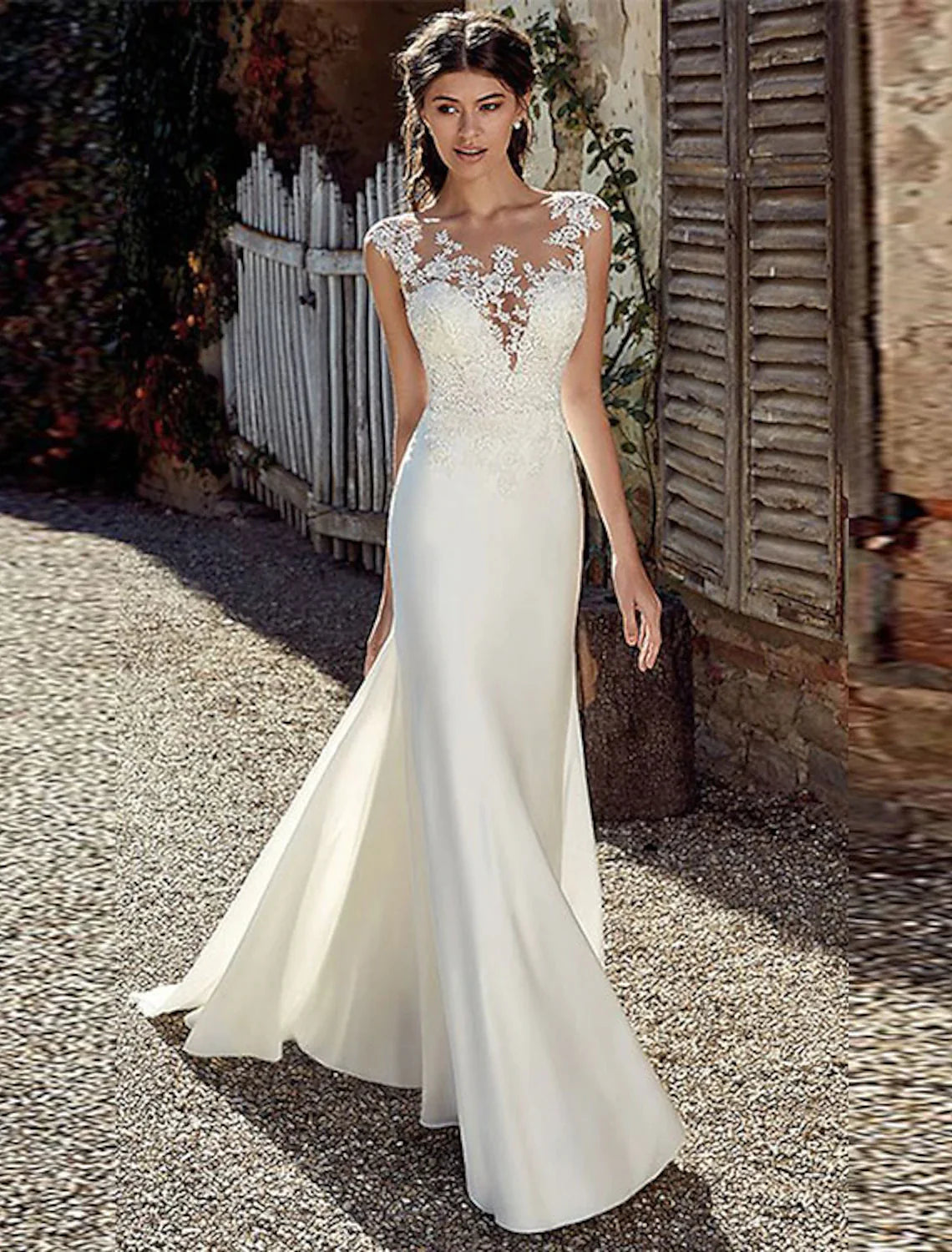 Model in a white mermaid wedding dress with cap sleeves and illusion neckline.