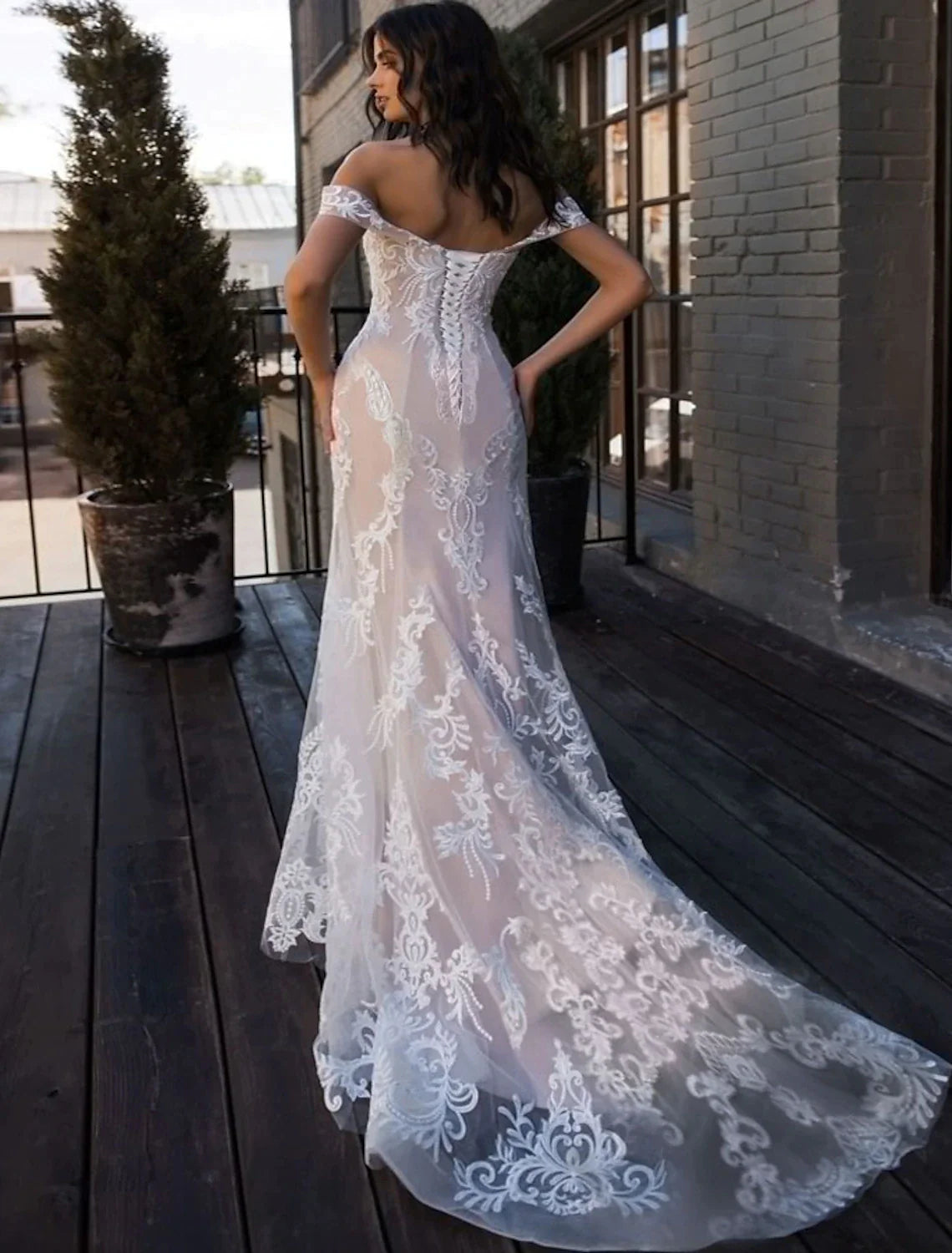 Back view of a bride in a white lace mermaid wedding dress, showcasing the court train and intricate lace details.