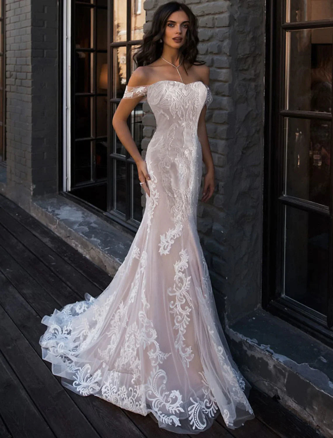 Close-up of the delicate lace details on the bodice and off-shoulder cap sleeves of the white wedding dress.