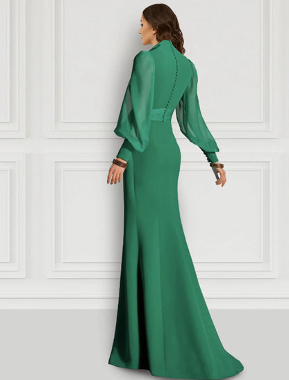 Woman posing in a flowing sage chiffon formal dress with strappy details.