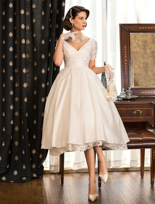 Front view of an elegant vintage A-Line white wedding dress with V-neck and short sleeves.