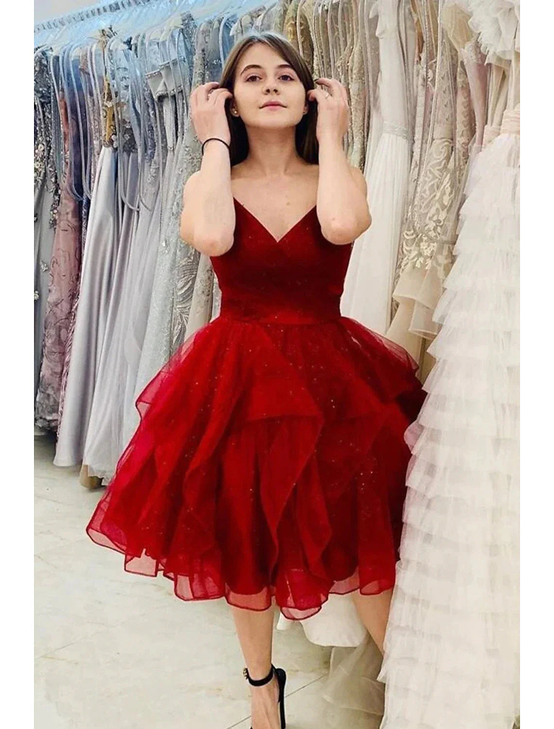 Model posing in a knee-length glitter tulle homecoming dress.