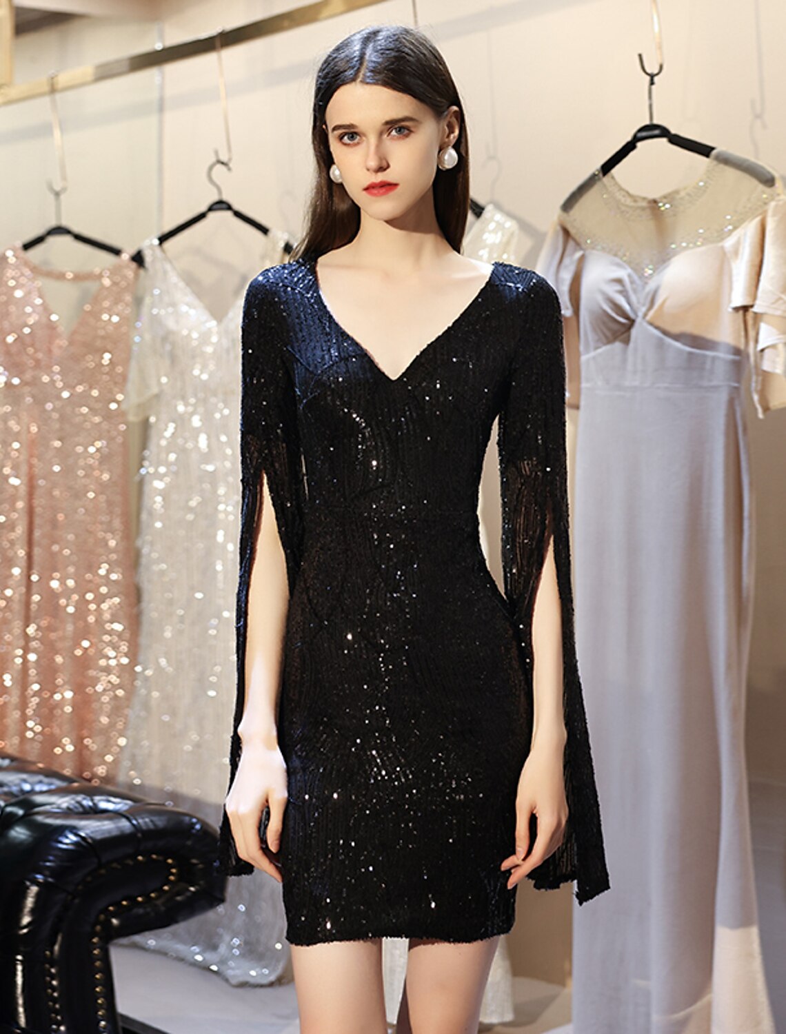 Model wearing a sparkling sequin sheath dress with a V-neck and long sleeves.