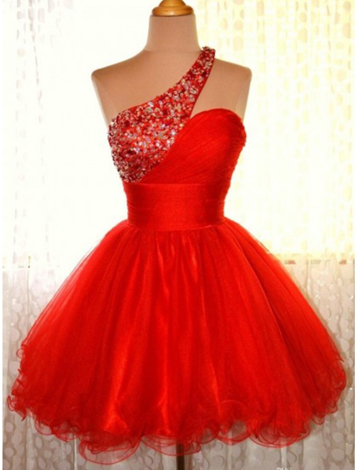 Woman wearing a sparkling A-line one-shoulder short homecoming dress with sequins and tulle.